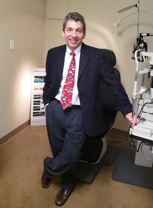 Optometrist in clinic exam room beside eye testing machine and chair