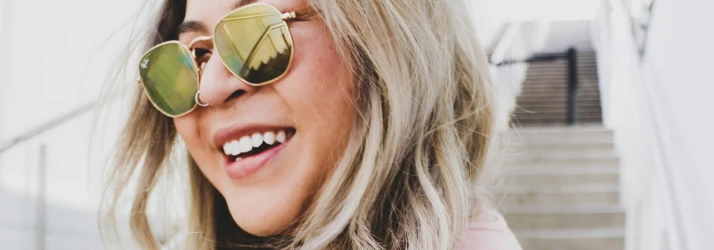 Close-up of a person smiling while wearing reflective sunglasses