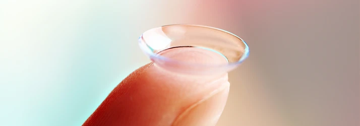 Close-up of a soft contact lens resting on the tip of a finger