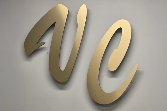 A gold "VC" sign on gray wall